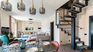 Ein moderner Essbereich mit Tisch für vier Personen, einer Treppe und einem Wohnzimmer im Hintergrund.