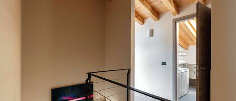 Eine Treppe mit Metallgeländer, Holzbalken an der Decke und einem Gemälde an der Wand.