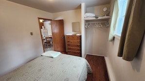 Ein Schlafzimmer mit Bett, Schminktisch, Spiegel und Ventilator.
