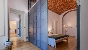Quarto com cama, mesa de cabeceira, um vaso e teto de tijolos.