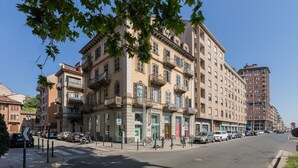 Um edifício com vários andares, varandas, um estacionamento e céu claro.