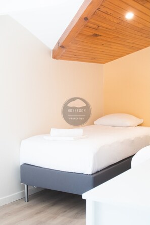 A modern bedroom with a bed, a wooden ceiling, and a logo on the wall. - Villa Igelak - Hossegor - Center - Lake - Pool (Soorts-Hossegor)