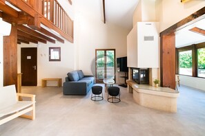 A spacious living area with a high ceiling, a sofa, two black stools, a small table, and a fireplace. - Villa Igelak - Hossegor - Center - Lake - Pool (Soorts-Hossegor)