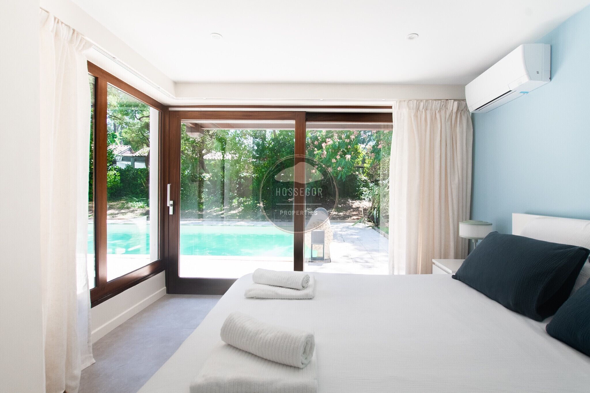 A bedroom with a large bed, a view of a swimming pool, and a sliding glass door.