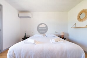 Ein Hotelzimmer mit Bett, rundem Spiegel, Wandklimaanlage und einem Schild mit dem Hotelnamen.