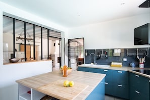 Eine moderne Küche mit einem Holztisch, blauen Schränken und einem großen Fenster.