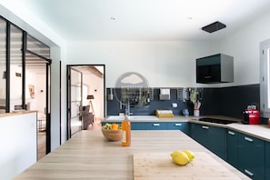 Eine moderne Küche mit einer Holz Arbeitsplatte, einem eingebauten Herd und einer hängenden Mikrowelle.