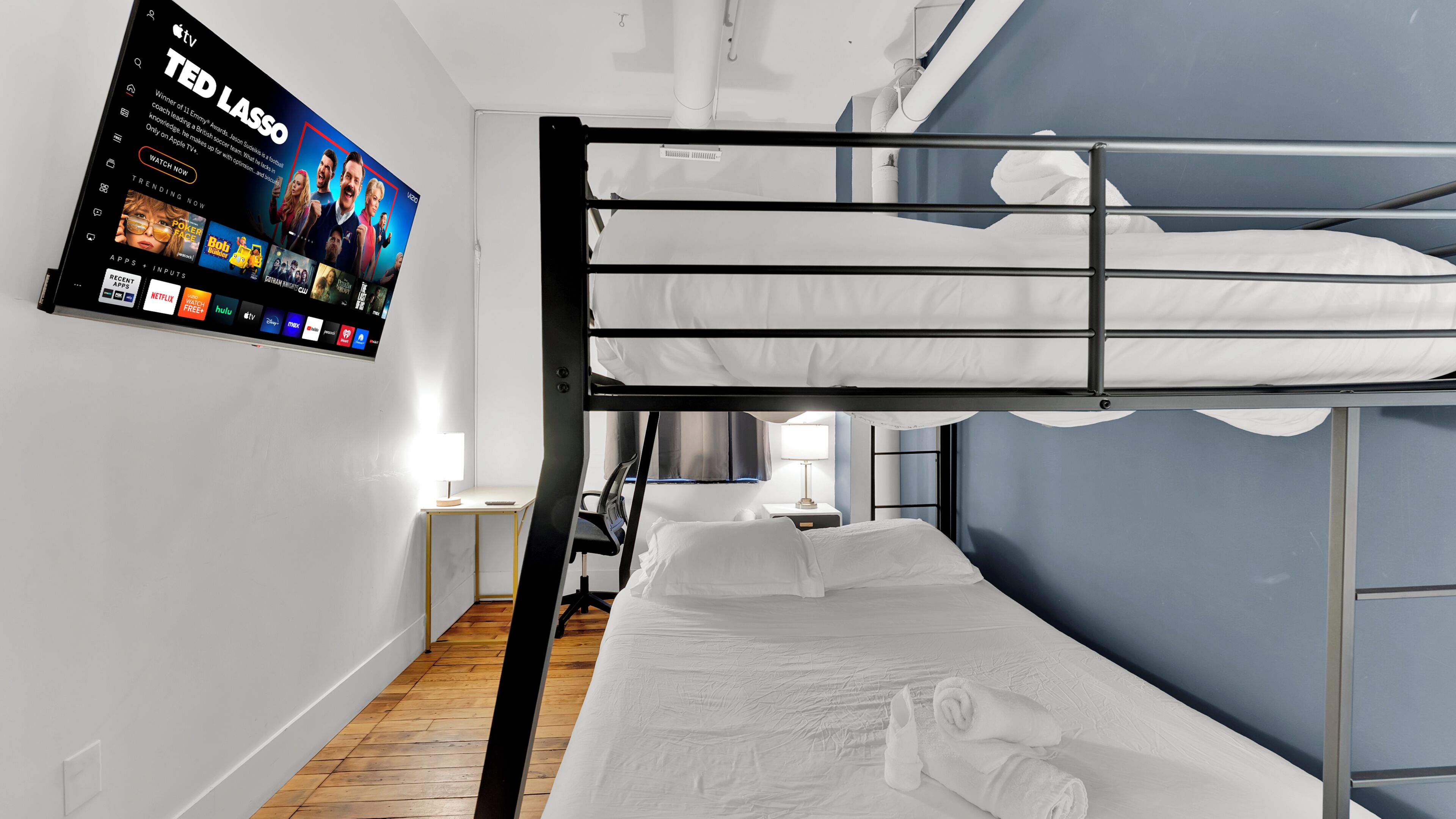A bunk bed room with a TV mounted on the wall displaying a sports channel.