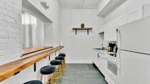 A modern kitchen with white cabinetry, a wooden bar counter, and black bar stools. - Apartmint at Arch St Philadelphia (Philadelphia)