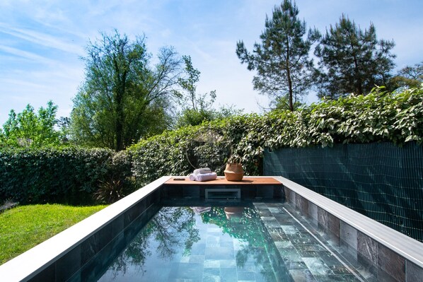 A rectangular swimming pool with a tiled edge, surrounded by lush greenery and trees. - Villa Alaïa - Hossegor - Cycle path - Shops (Soorts-Hossegor)