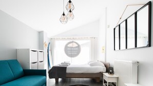 A modern bedroom with a bed, a sofa, a bedside table, a radiator, and a wall-mounted TV. - Villa Alaïa - Hossegor - Cycle path - Shops (Soorts-Hossegor)