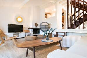 A modern living room with a flat-screen TV, wooden furniture, a fireplace, and a staircase. - Villa Patio - Seignosse - Forest - Beach - Quiet (Seignosse)