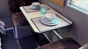 Un interior acogedor con una mesa dispuesta para comer, un mapa mundial en la pared y una ventana con cortinas.