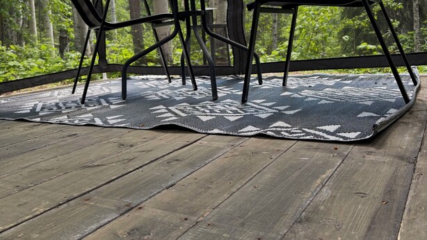 Una terraza de madera con una mesa y sillas, rodeada de un bosque.