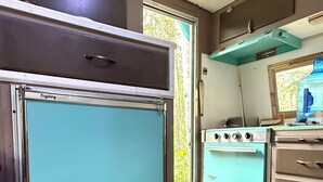 Una cocina compacta con refrigerador, estufa y armarios.