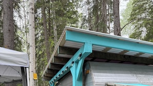 Una casa móvil con fachada turquesa, un porche cubierto y una terraza de madera.