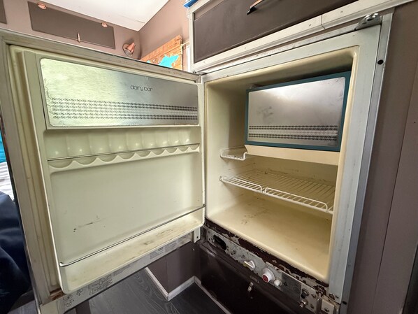 An open refrigerator with a label, a shelf, and a control panel.
