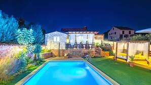 A swimming pool with a patio area, a brick house, and a well-lit garden at night. - Villa Nicoletta (Polaca)
