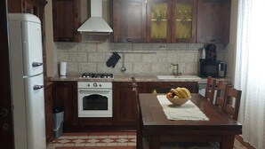 A kitchen with a stove, oven, refrigerator, and a dining table with chairs. - Villa Nicoletta (Polaca)