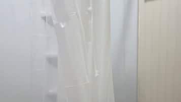 Une salle de bain avec un rideau de douche, un porte-serviettes et des toilettes.