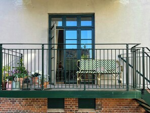 Ein Balkon mit Metallgeländer, einer Bank und Topfpflanzen.