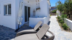 A white building with a balcony, wicker lounge chairs, a small table, and hanging planters. - Ambela House, Traditional Living in Kefalos, Kos (Kos)