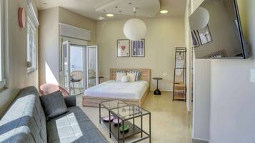 A bedroom with a bed, a sofa, a glass coffee table, a small round table, and a wardrobe.
