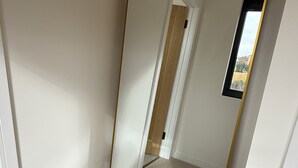 Ein Zimmer mit einem großen Spiegel, Teppichboden und einer Tür zu einem weiteren Raum.