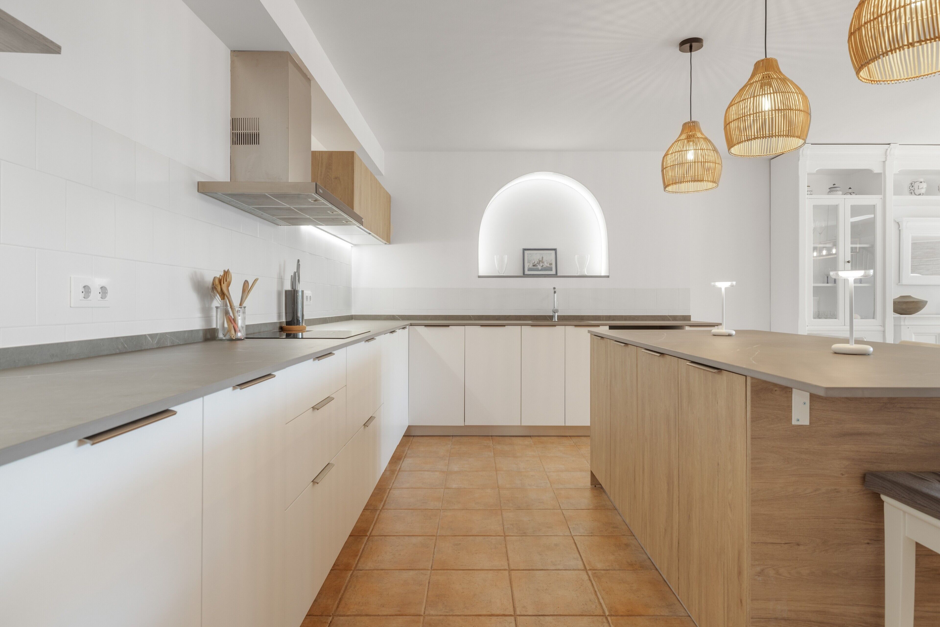 Een moderne keuken met witte kasten, een houten eiland en hanglampen.