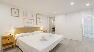 Ett hotellrum med en stor säng, sängbord, en garderob och inramade konstverk på väggen.