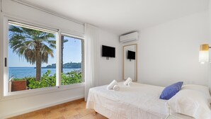 Un dormitorio con cama, televisor y vista al mar.