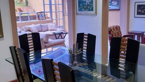 A dining area with a glass table and chairs, a sofa, and a view of the outside. - Exclusive House in Chapinero Alto - Corporate Groups & Wellness Retreats (14 guests) (Bogotá, D.C.)
