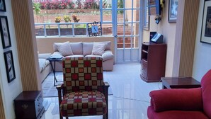 A living room with a glass coffee table, a red sofa, a patterned armchair, and a view of a garden through a glass door. - Exclusive House in Chapinero Alto - Corporate Groups & Wellness Retreats (14 guests) (Bogotá, D.C.)