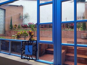 Una ventana con un reloj, un muro de ladrillo y un jardín con diversas plantas y flores.