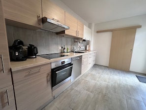 A modern kitchen with a built-in oven, a coffee maker, and a sink.