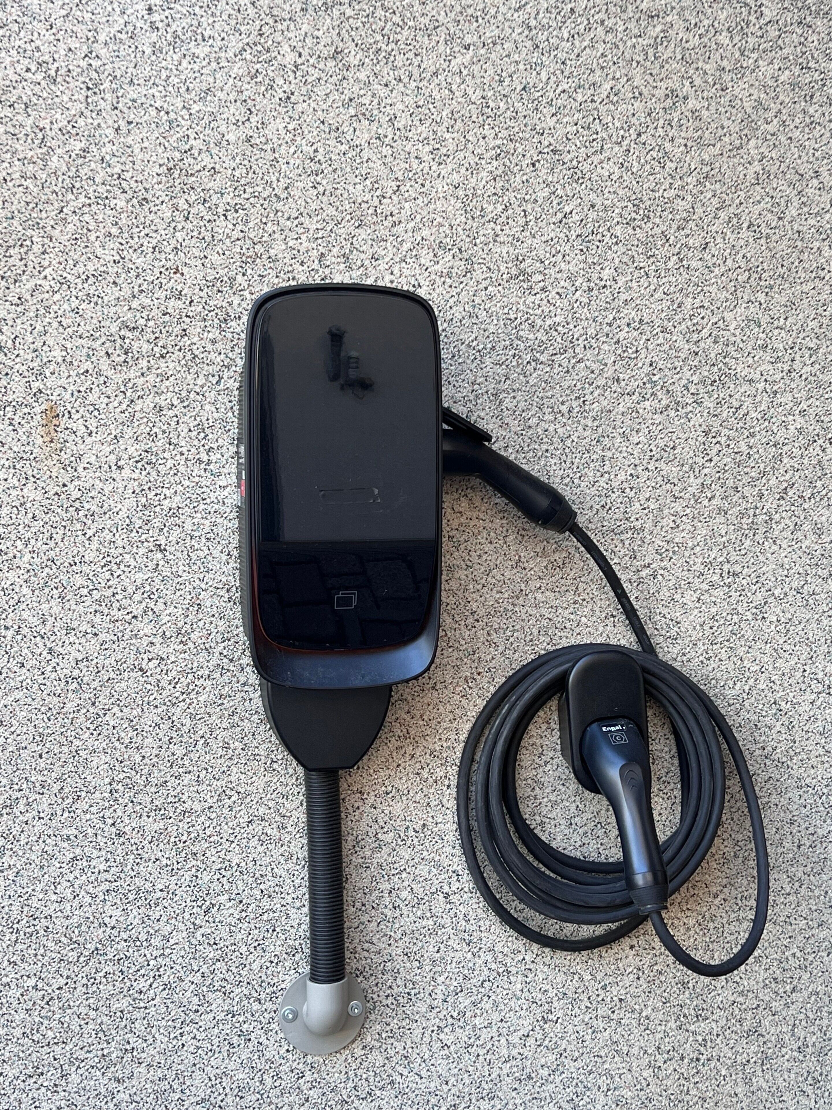 A portable power station with a cable and a plug, placed on a textured surface.