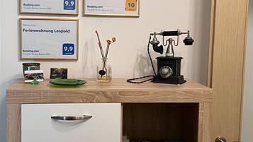A desk with framed awards, a vintage telephone, and a small vase with reeds.