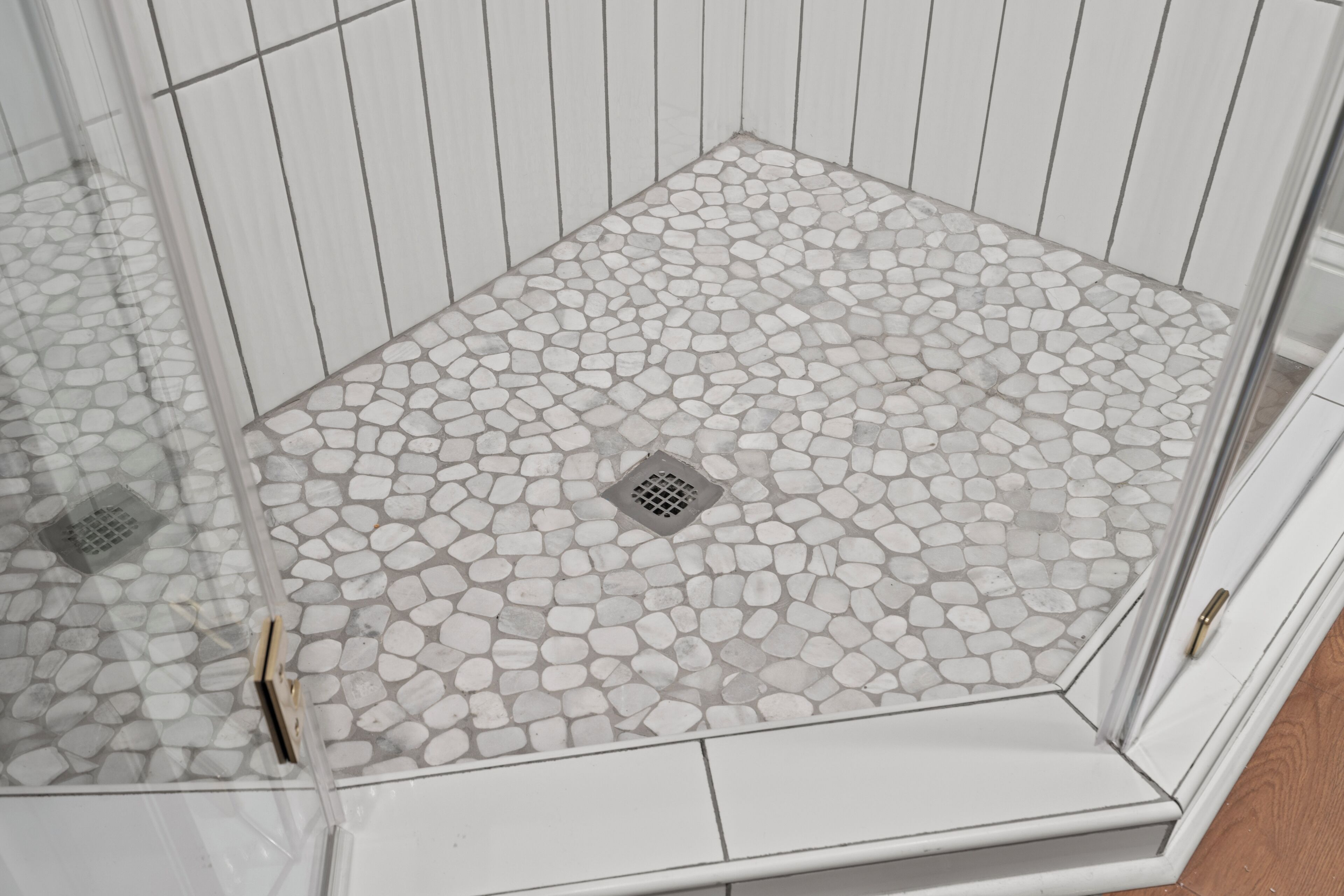 A shower with a pebble-patterned floor and a drain in the center.