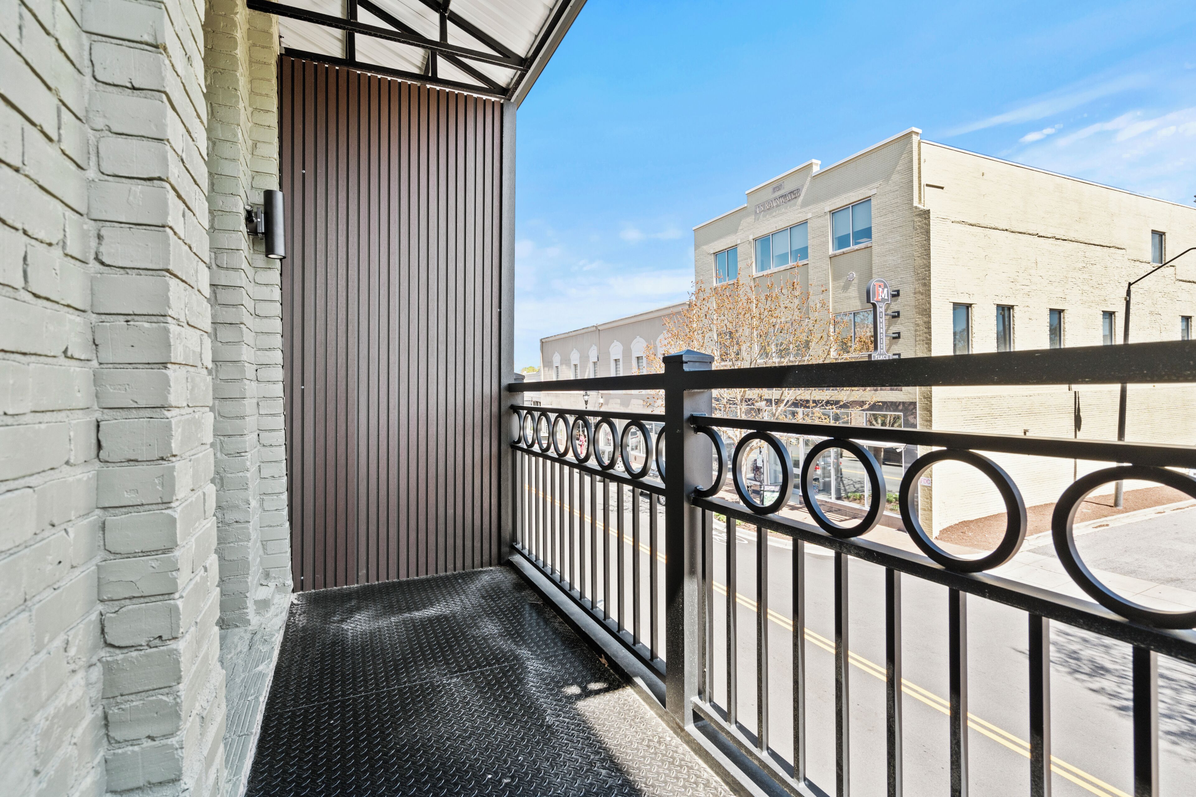 A balcony with a metal railing, a door, and a building in the background.