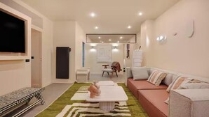 A modern living room with a sofa, a coffee table, a TV, and a patterned rug. - JUST MOMENTS FROM ICONIC THE PICASSO MUSEUM, PLACE DES VOSGES - RUE DES ARCHIVES (Paris)