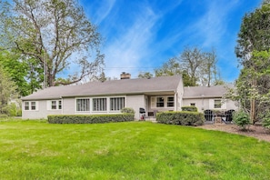 A two-story house with a front porch, a lawn, and trees in the background.