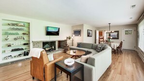 Una sala de estar con chimenea, televisor, sofá y mesa de centro.