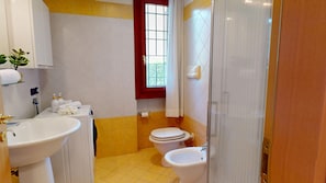 A bathroom with a sink, two toilets, a window, and a shower area. - Freestyle Apartment By Bookinggardalake (Salò)