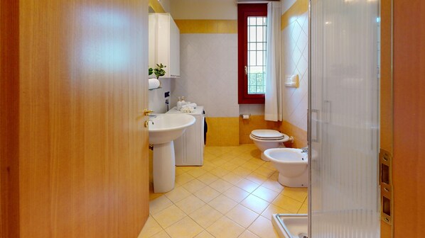 A bathroom with a sink, toilet, bidet, and a shower area. - Freestyle Apartment By Bookinggardalake (Salò)