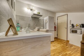 A compact kitchen with a white countertop, a built-in microwave, and a small refrigerator. - The Refuge of Manu - Lucca (Lucca)