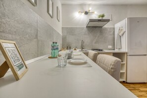 A modern kitchen with a long countertop, a built-in stove, and a refrigerator. - The Refuge of Manu - Lucca (Lucca)