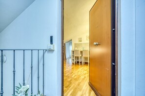 A hallway with a wooden door, a staircase, and a dining area with chairs and a table. - The Refuge of Manu - Lucca (Lucca)