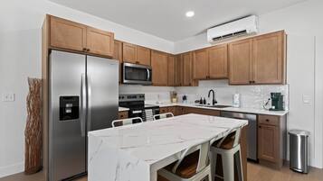 A modern kitchen with stainless steel appliances, wooden cabinets, and a marble island.