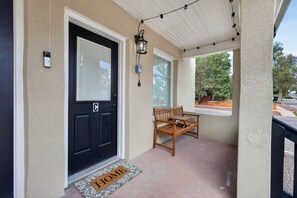 A black door with a window, a bench, and a doormat with 'HOME' on it.