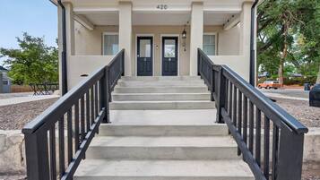A building with a double door entrance, a set of concrete steps, and a black metal railing.